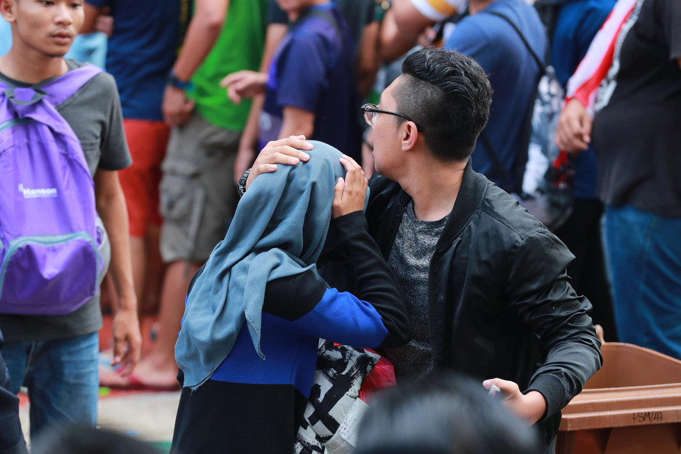 Nhiều CĐV Malaysia đã che chở cho người thân tránh khỏi bị thương trong quang cảnh hỗn loạn này - Ảnh: Nguyễn Khánh