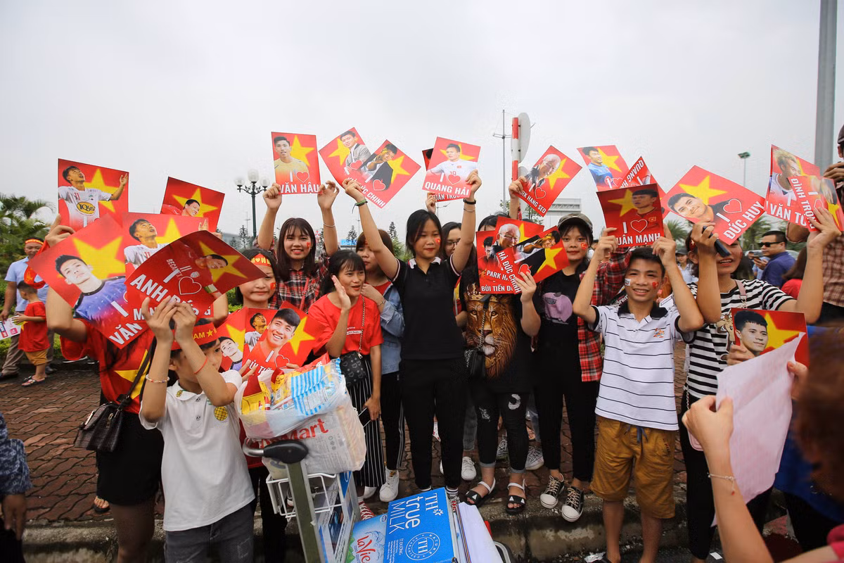 Tại khu vực gần cổng sân bay Nội Bài, số lượng người hâm mộ đổ về đây mỗi lúc một đông, không khí vô cùng tưng bừng, náo nhiệt.