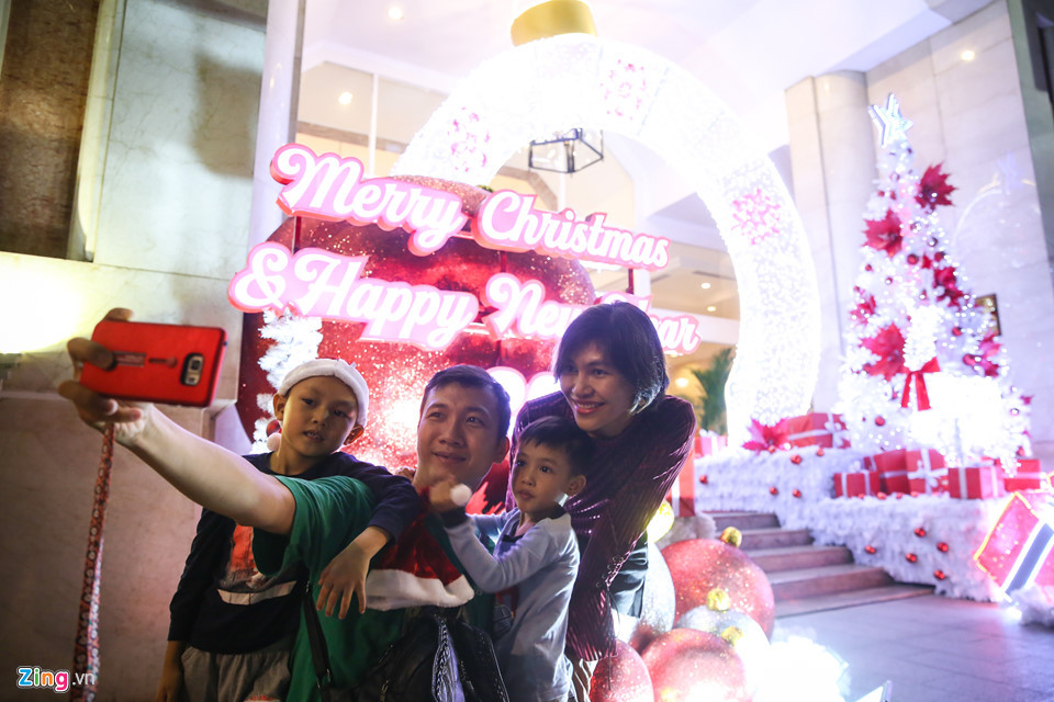 Trên đường Nguyễn Huệ, gia đình anh Đoàn Đức Linh và chị Nguyễn Lê Hoài Phúc (ngụ quận Tân Bình) đang chụp ảnh lưu niệm cùng tiểu cảnh trang trí trước một khách sạn tại đây. Anh chị cho biết mùa Giáng sinh năm nay, các nẻo đường trang trí không bắt mắt bằng những năm trước.