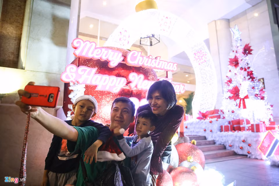 Trên đường Nguyễn Huệ, gia đình anh Đoàn Đức Linh và chị Nguyễn Lê Hoài Phúc (ngụ quận Tân Bình) đang chụp ảnh lưu niệm cùng tiểu cảnh trang trí trước một khách sạn tại đây. Anh chị cho biết mùa Giáng sinh năm nay, các nẻo đường trang trí không bắt mắt bằng những năm trước.