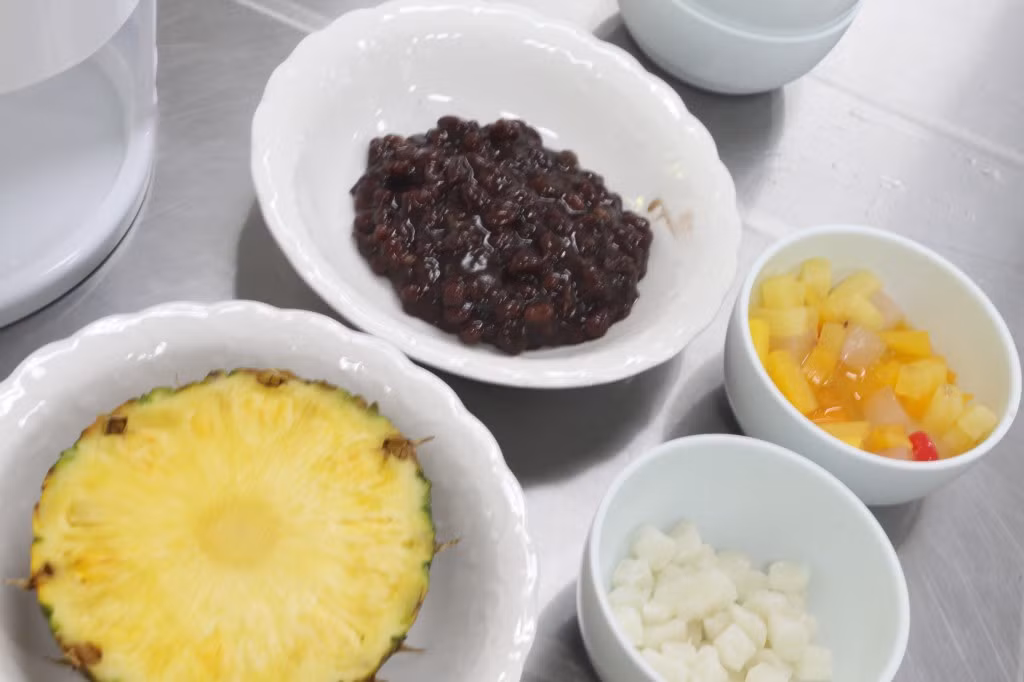 Nguyên liệu để làm món patbingsu Hàn Quốc gồm: Đậu đỏ 225g; Nước 11ml; Đường cát 225g; Dưa hấu, dứa; Hạt ngũ cốc; Sữa tươi; Sữa đặc; Bánh nếp Hàn Quốc...Ngoài ra bạn có thể cho thêm các hoa quả khác như kiwi, chuối, dâu tây...tùy khẩu vị.