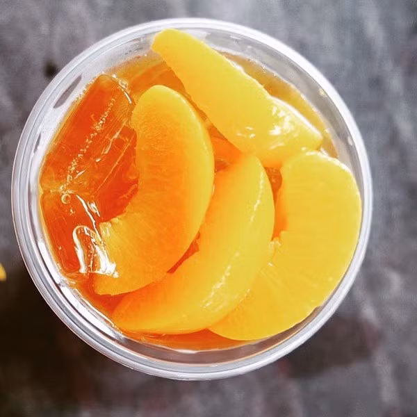 Bước 6. Để pha trà đào ngon đúng điệu, 1 gói trà đào nhúng; 50ml nước nóng; 40ml nước đào ngâm. Trước tiên, bạn cần nhúng túi trà đào (hoặc trà đen) vào ly nước nóng, sau đó cho nước đào ngâm và miếng đào đã trữ lạnh vào khuấy tan, thêm đá lạnh là bạn đã có cốc trà đào ngon tuyệt rồi.