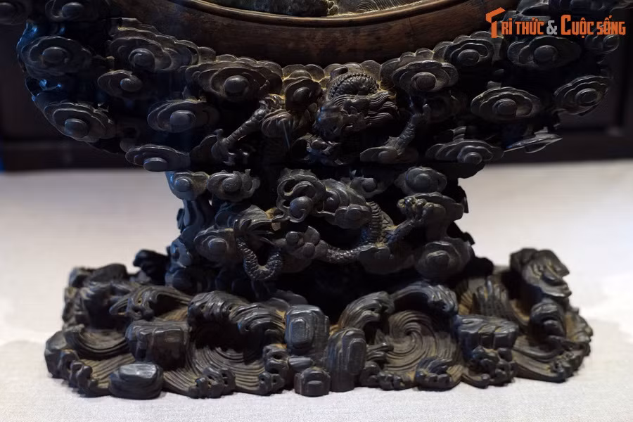Phần đế bằng gỗ của bức phù điêu cũng được tạo tác hết sức tinh xảo, thể hiện hình tượng rồng vờn mây, giỡn sóng.