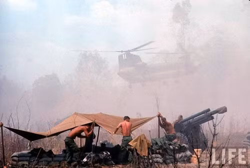 Binh sĩ Mỹ bố trí nơi chiến đấu. Đằng sau là một chiếc trực thăng quân sự đang hoạt động khiến bụi bay mù mịt.