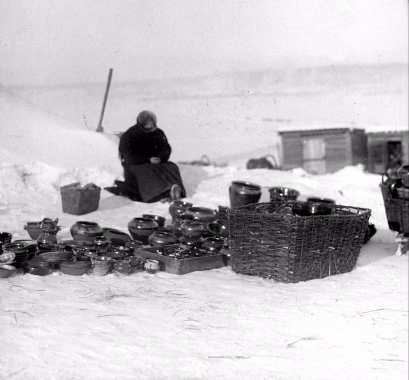 Bà cụ ngồi co ro trong rét bên cạnh rất nhiều bình, lọ, chum... bên ngoài trời.