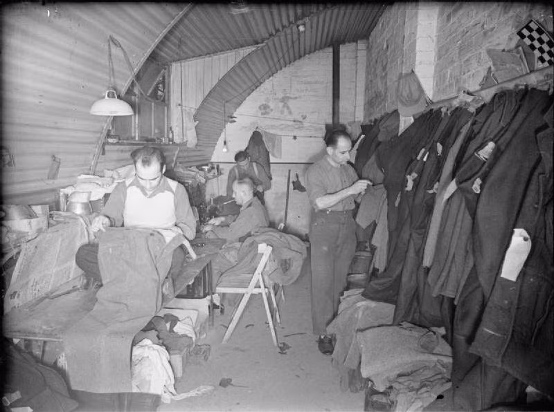 Tù binh chiến tranh Đức may vá quần áo trong một cửa hàng may quần áo ở trại tập trung của Anh.