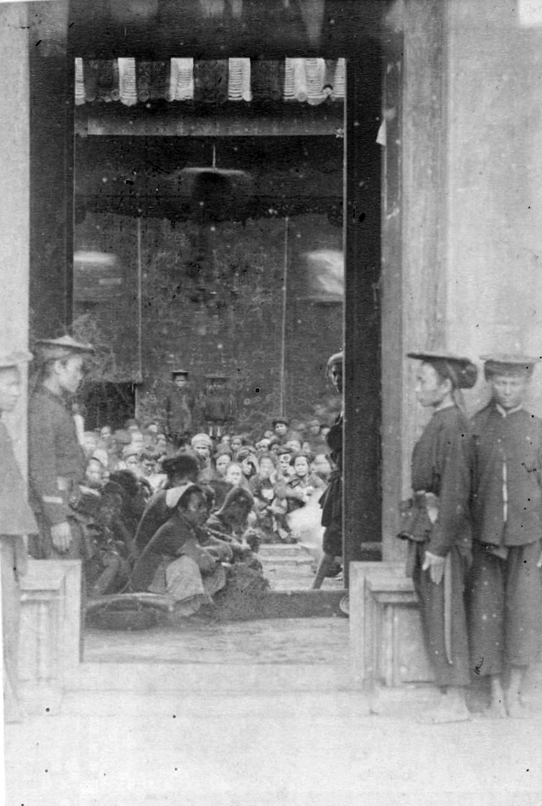 Những người lao động chân tay - cu li (coolies) - được người Pháp trưng dụng đang tề tựu tại một nhà kho, ngoài cổng có những nhân viên bảo vệ người Việt trông giữ.