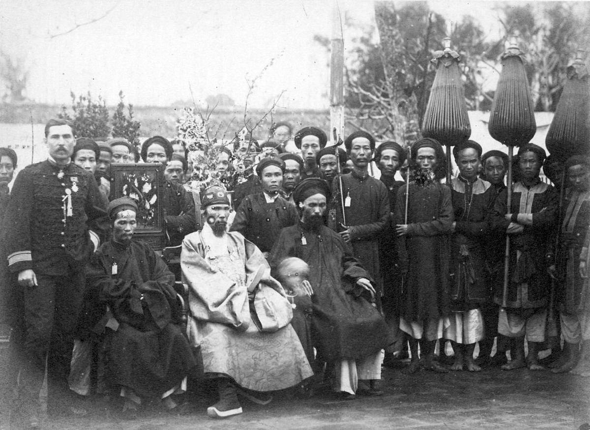 Tổng đốc Hà Nội Nguyễn Hữu Độ (trang phục sáng màu) ngồi giữa các quan dưới quyền và đoàn tùy tùng... Bên trái là quan Trú sứ Pháp Parreau với viên thông ngôn, Hà Nội năm 1885. Ảnh: Xavier Brau de Saint-Pol Lias / Gallica.bnf.fr.