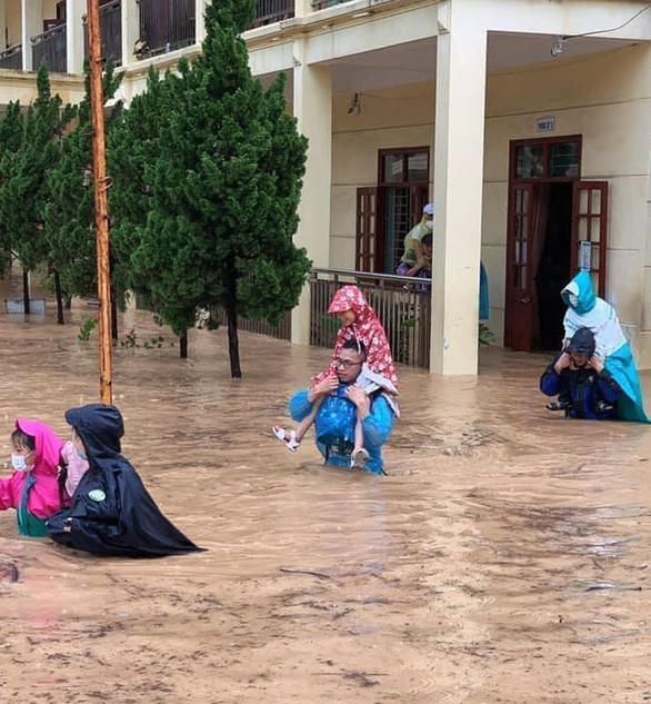 Nhiều phụ huynh chủ động cuốc bộ đến Trường tiểu học Trần Quốc Toản để đón con vì mưa ngập sâu.