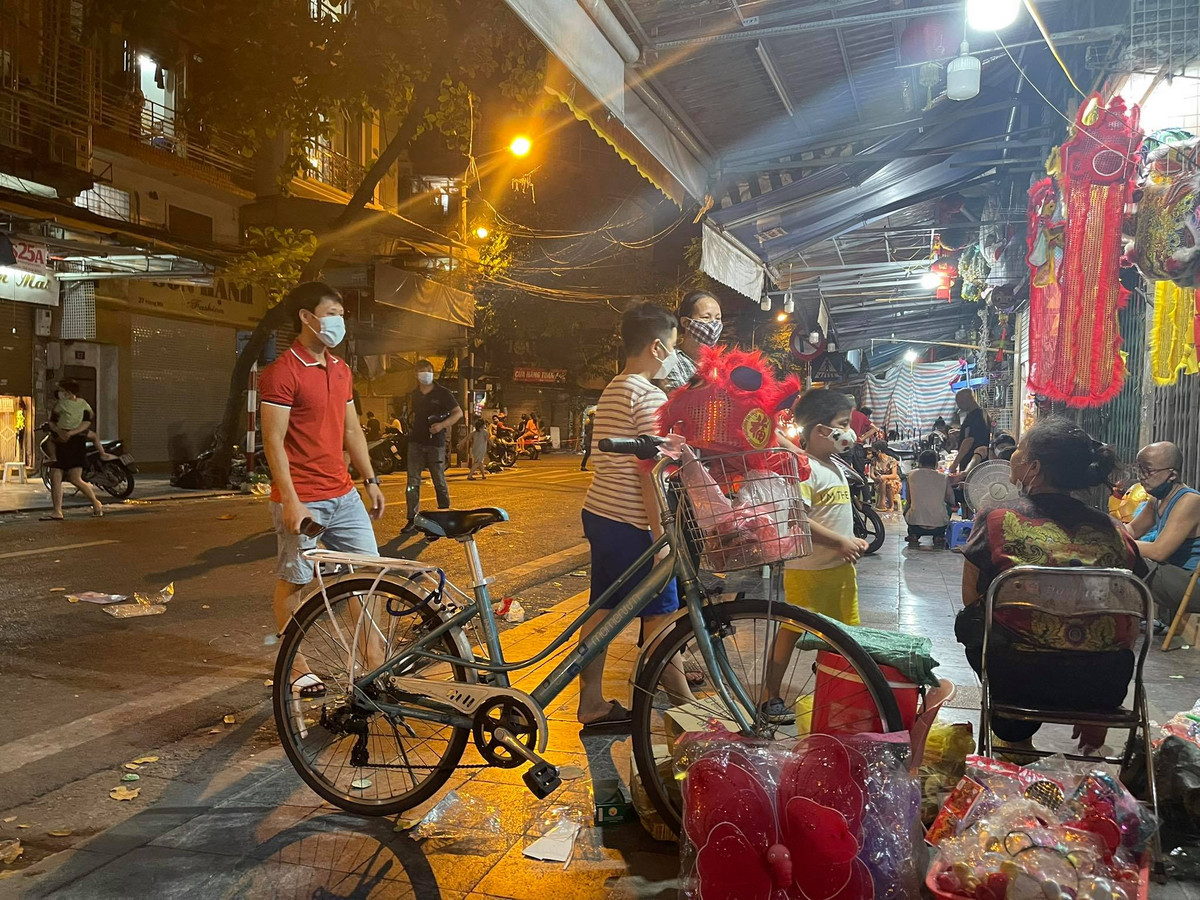Người dân đưa con mình đi mua đồ trung thu nhưng vẫn đeo khẩu trang đầy đủ.