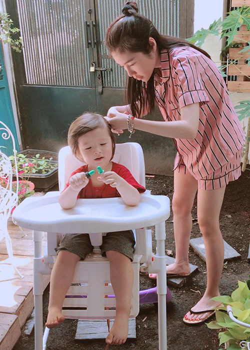 Hình ảnh bé Túc Mạch ngồi ngoan ngoãn để mẹ cắt tóc.