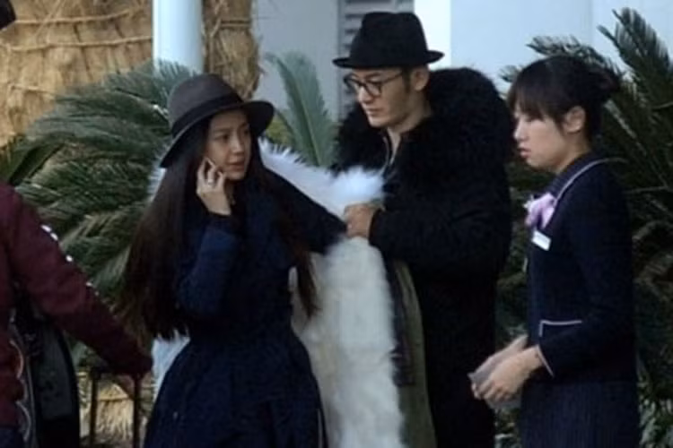 Huỳnh Hiểu Minh ân cần mặc áo cho Angelababy ở sân bay. Ảnh: QQ