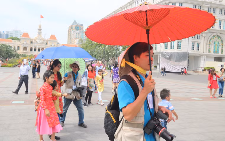 Du khách xúng xính trong những chiếc áo dài truyền thống với đủ kiểu chống nắng để dạo chơi tại đường hoa.