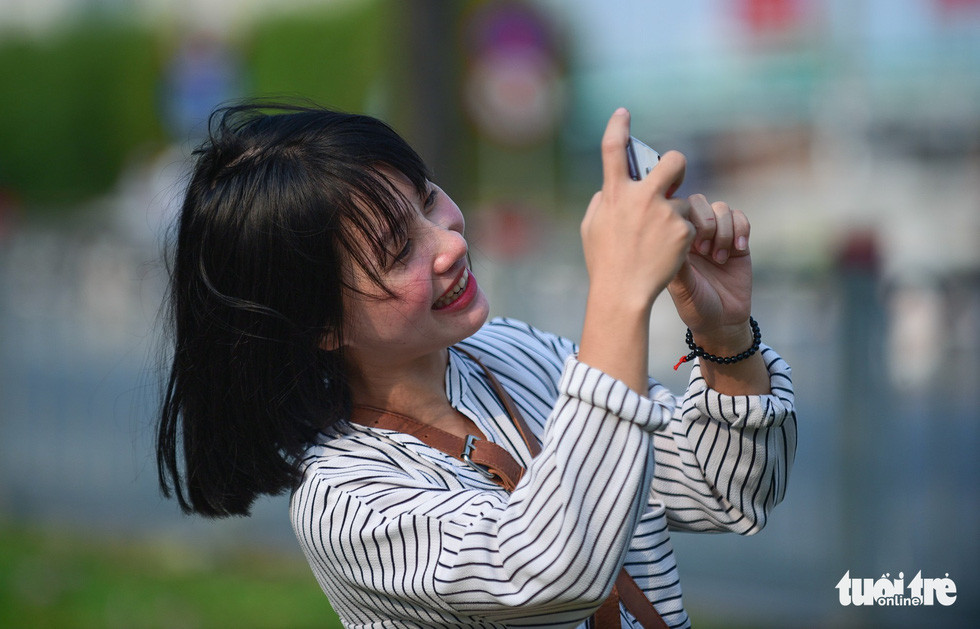 Chụp hình check-in tại hàng cây kèn hồng phía cửa hầm Thủ Thiêm - Ảnh: THUẬN KHÁNH