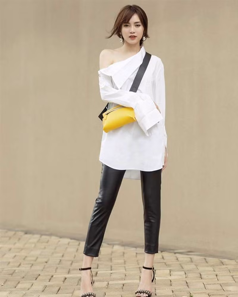 Sơ mi trắng lệch vai kiểu cách được Ninh Dương Lan Ngọc ghép đôi với quần da và sandals cao gót theo phong cách tối giản mà vẫn cực kì chất.