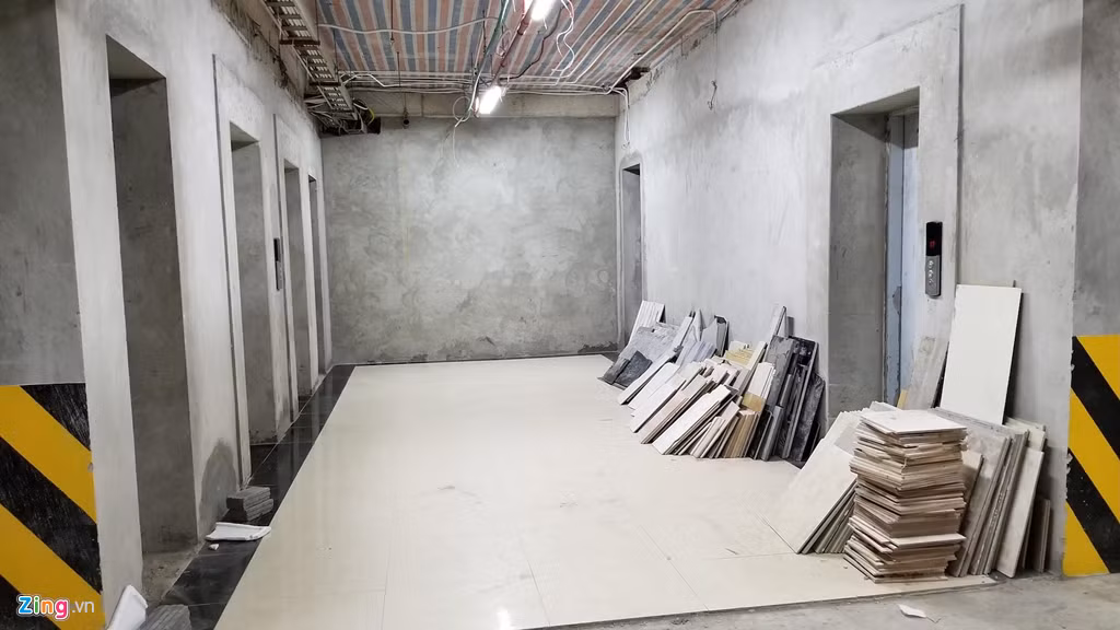 Dưới tầng hầm gửi xe, vật liệu xây dựng ngổn ngang, hệ thống thang máy chưa hoàn thiện. Cư dân ở đây cho biết họ bất bình mỗi khi gửi, lấy xe phải tiếp xúc với bụi, bẩn của vật liệu xây dựng.