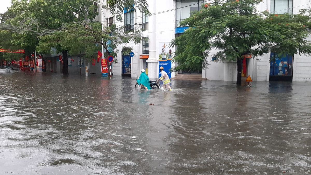 Do ảnh hưởng bão số 2, đường phố bị ngập CSGT lội nước giúp đỡ người tham gia giao thông.