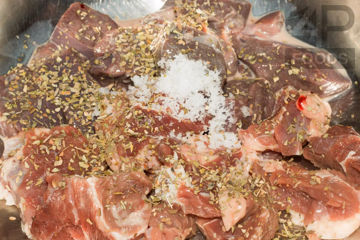 Giờ cho gan đã ngâm qua sữa tươi và thịt bò thái miếng vừa ăn vào trong 1 cái tô lớn, sau đó cho thêm 1 thìa muối, 1/2 thìa ăn cơm đường và 1 thìa ăn cơm lá oregano khô đảo đều để ướp.