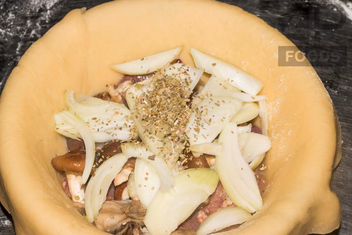 Cho thêm hành tây thái lát và rắc bột lá oregano.