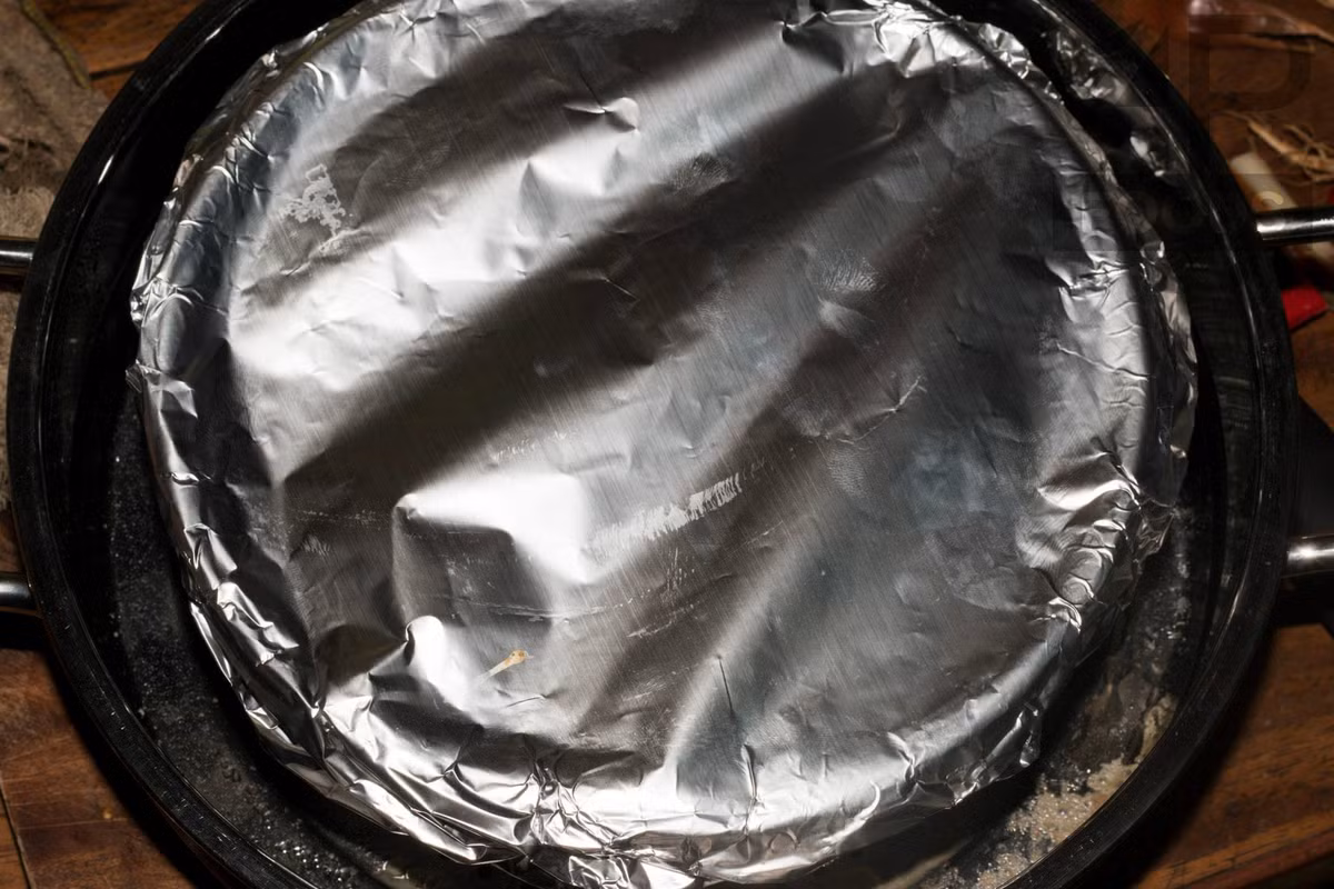 Dùng giấy bạc bọc kín khuôn bánh lại để nướng và hấp chín. Bạn cần cho bánh vào nồi hấp cách thủy trong khoảng 5 tiếng đồng hồ.