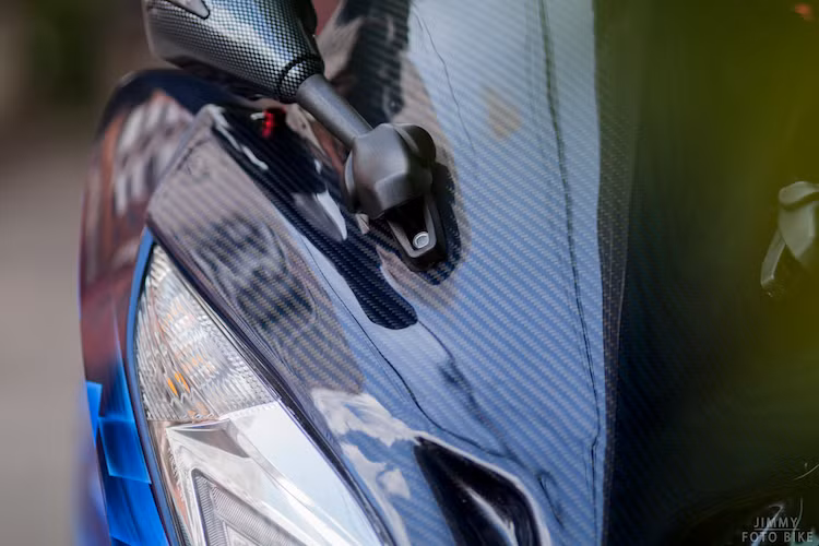 Sử dụng một số "đồ chơi" nhập, một biker Sài Gòn đã độ kiểng nhẹ nhàng PCX để chiếc xe trở nên hấp dẫn hơn. Ở phía trước, chiếc xe đã được trang bị kính chắn gió bằng sợi carbon, bên cạnh đó là gương chiếu hậu tích hợp xi-nhan cũng được sơn giả carbon đẹp mắt.