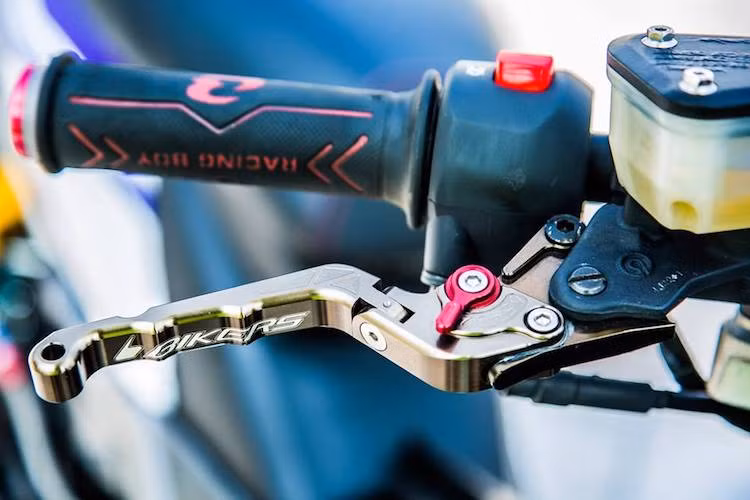 Chi tiết quan trọng nhất giúp Exciter có dáng giống xe thể thao Yamaha X1R là ghi-đông trần kèm chảng 3 đã được chủ xe trang bị. Phía trên tay lái, của xe có một số "đồ chơi" như bao tay Racing Boy, tay phanh Bikers và cùm tay côn Bikers.