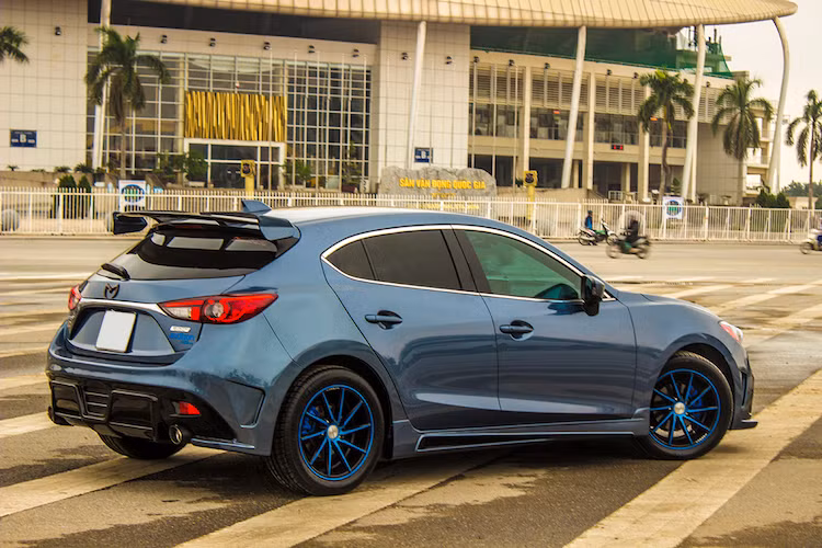 Ở hai bên thân xe, "dàn chân" của Mazda 3 cũng đã được nâng cấp lên với bộ vành "hàng hiệu" Vossen CVT 10 cánh kép xoắn kích thước 17 inch, được sơn màu xanh kiểu siêu xe BMW i8 và bọc quanh bằng lốp Michelin Pilot Sport 3 thể thao.