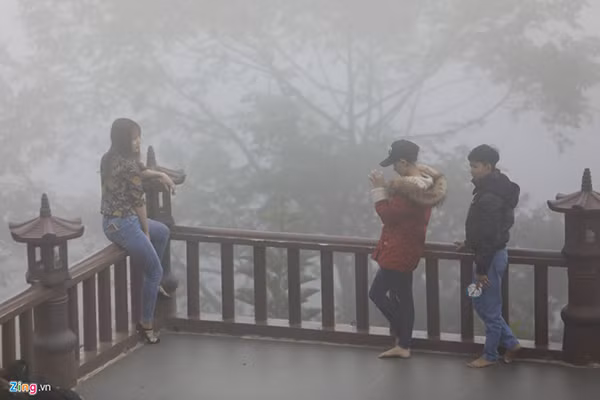 Một cô gái ngồi lên lan can chùa để tạo dáng.