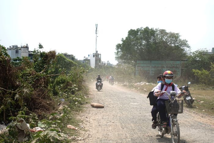 Những ngày nắng khô, con đường mù mịt bụi đường, hai bên đường trở thành nơi chứa rác thải. Dòng nước dưới kênh bị bèo phủ kín, khi thời tiết nắng nóng bốc lên mùi khó chịu. (Ảnh: Tiền Phong).