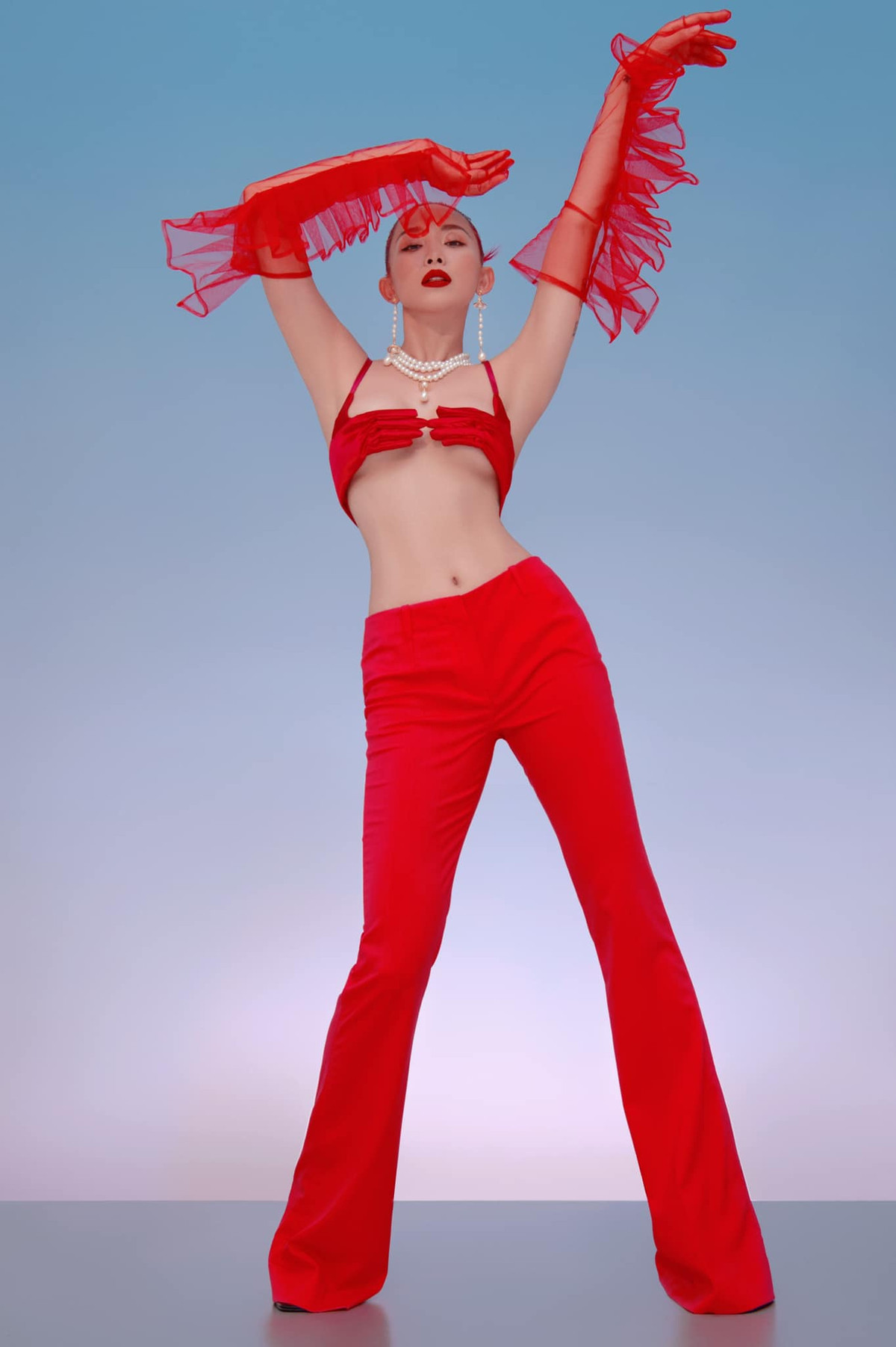 Diện set đồ tông đỏ với chiếc áo ngực "bàn tay hư", nữ ca sĩ khéo khoe vòng 1 lấp ló, eo thon cùng đôi chân dài thẳng tắp.