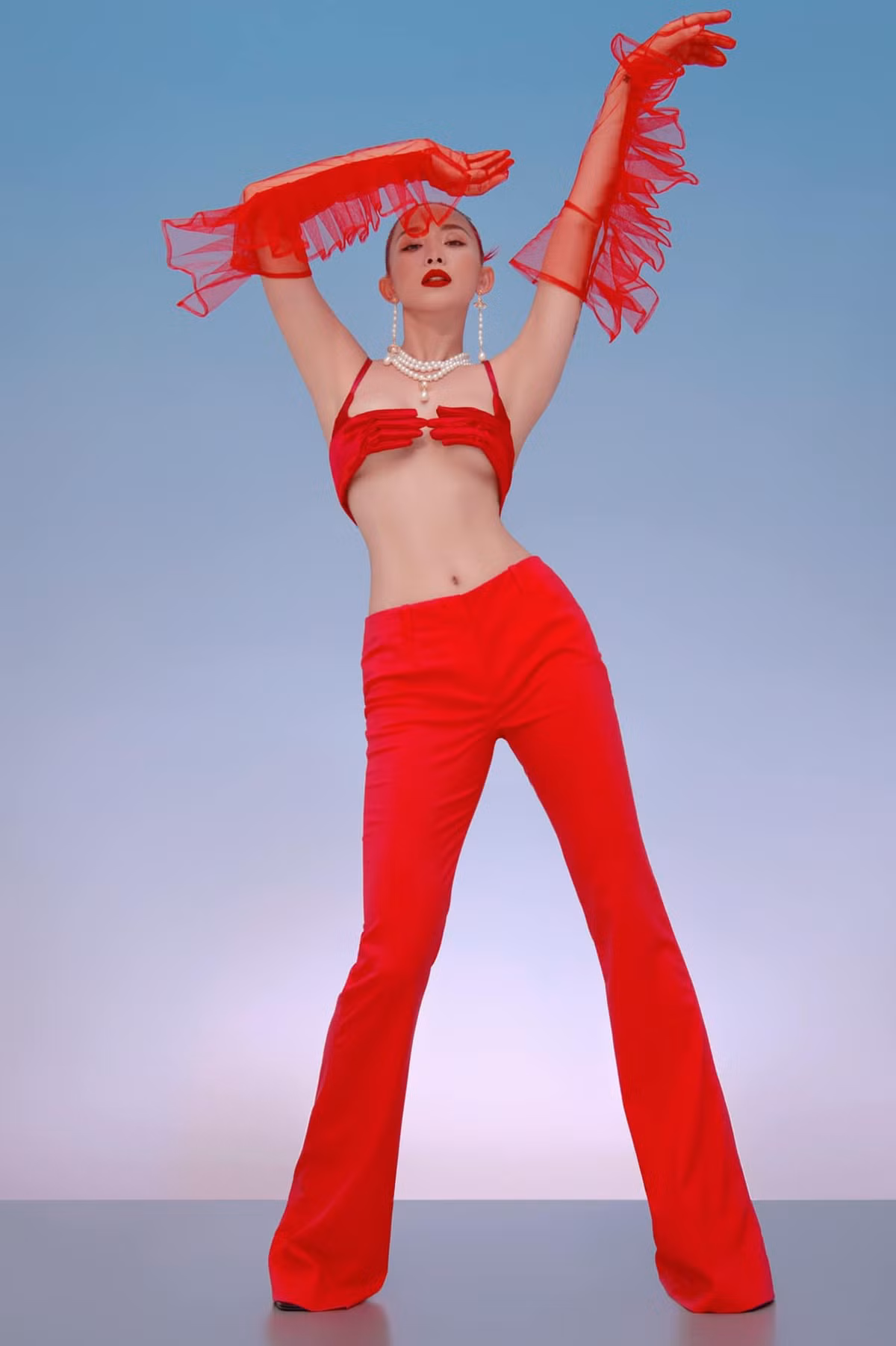 Diện set đồ tông đỏ với chiếc áo ngực "bàn tay hư", nữ ca sĩ khéo khoe vòng 1 lấp ló, eo thon cùng đôi chân dài thẳng tắp.