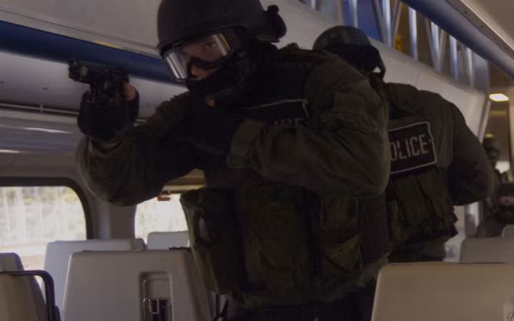 Một quân cảnh trang bị súng ngắn M9 dẫn đầu đội SRT tiến dọc bên trong một toa tàu hỏa.