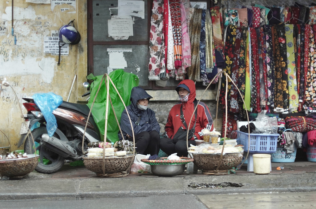 Hai người bán hàng rong nhà ở Thanh Trì đã phải dậy đi chợ bán hàng từ rất sớm. Hôm nay trời lạnh hàng ế nên các chị đã phải nán lại để mong bán được hết hàng.