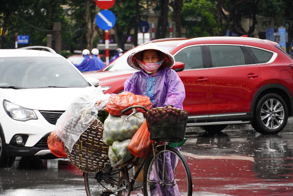 Do không khí lạnh tràn về quá bất ngờ, nhiều người dân chưa kịp chuẩn bị áo ấm, đành phải sử dụng áo mưa để tránh rét.