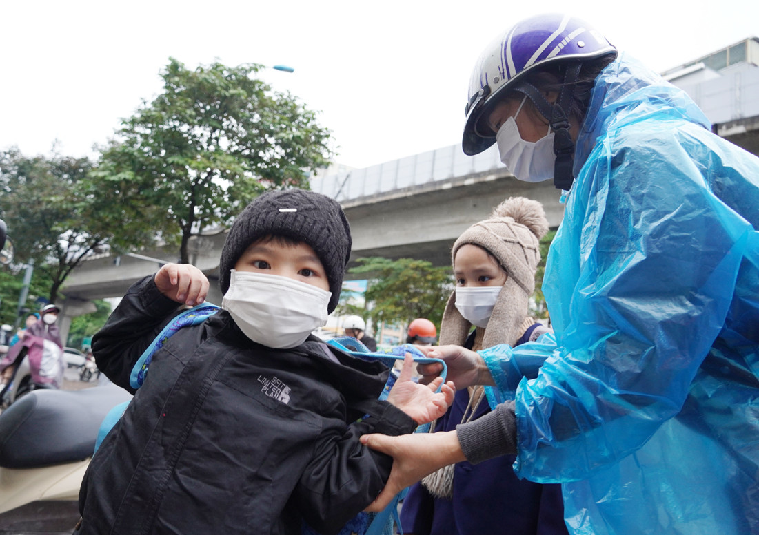 Các bé được bố mẹ đưa đến trường với mũ len và áo khoác giữ ấm.