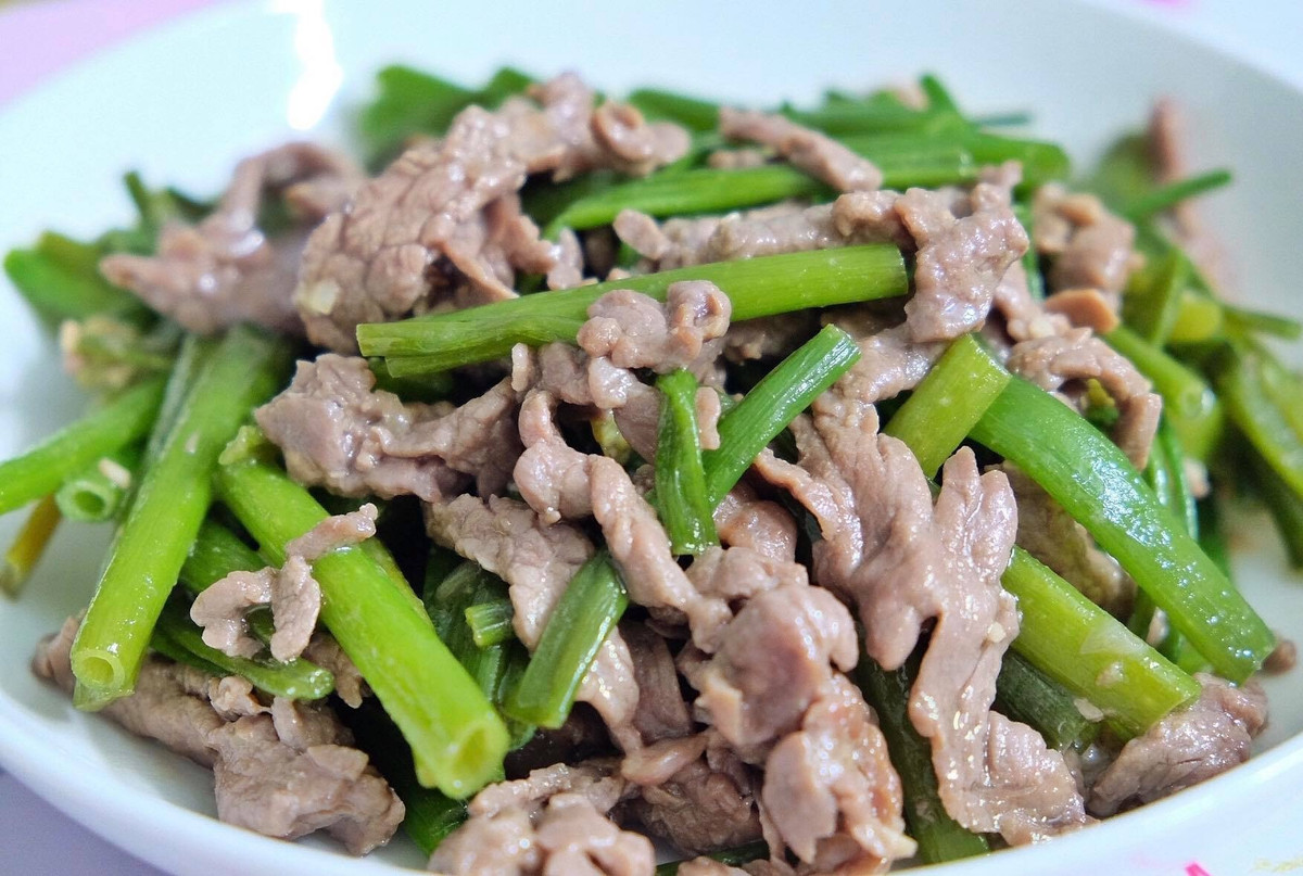 Tiếp đến, phi thơm dầu với tỏi, cho bông hẹ vào xào đều đến chín. Cho thịt bò vào xào, thêm ít tiêu xay, hành ngò cắt đoạn là xong.