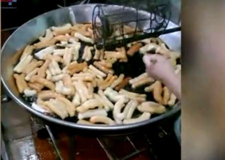 Mặc dù chảo dầu rán đã ngã màu đen ngòm nhưng người làm bánh vẫn tận dụng để rán quẩy từ lượt này sang lượt khác. Ảnh cắt từ clip.