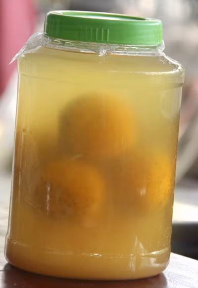 Rượu ngâm cam Xã Đoài trong các chum lớn sau khi đã đạt chuẩn sẽ được san chiết sang các chai và bán cho khách hàng với giá 100.000 đồng/chai. Ảnh: Giadinhnet.