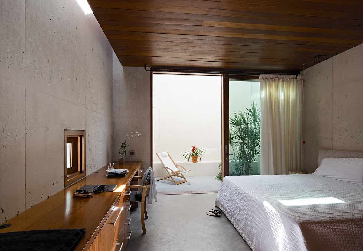 Phòng ngủ với trần nhà được ốp gỗ, điểm xuyết bởi những chậu cây xanh, mang lại cảm giác gần gũi với thiên nhiên.