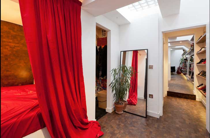 Một phòng ngủ ấm áp, nổi bật với tấm rèm đỏ, cạnh đó là phòng thay đồ, để giày dép.