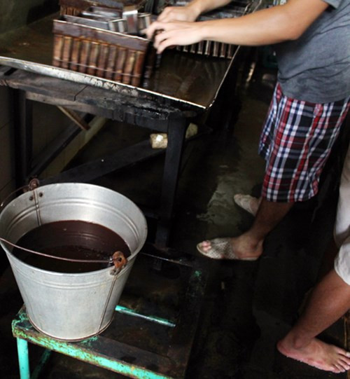 Phụ gia làm kem được đựng trong những xô sắt, chỉ cần với loại nước màu nâu đen như vậy sẽ có thể tạo ra hàng loạt cây kem vị socola thơm ngon thu hút khách hàng. Ảnh: ANTĐ.