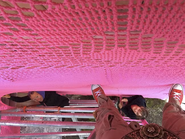 Sau khi đan xong chiếc áo khổng lồ, người dân địa phương đã giúp đỡ lồng áo vào nhà.