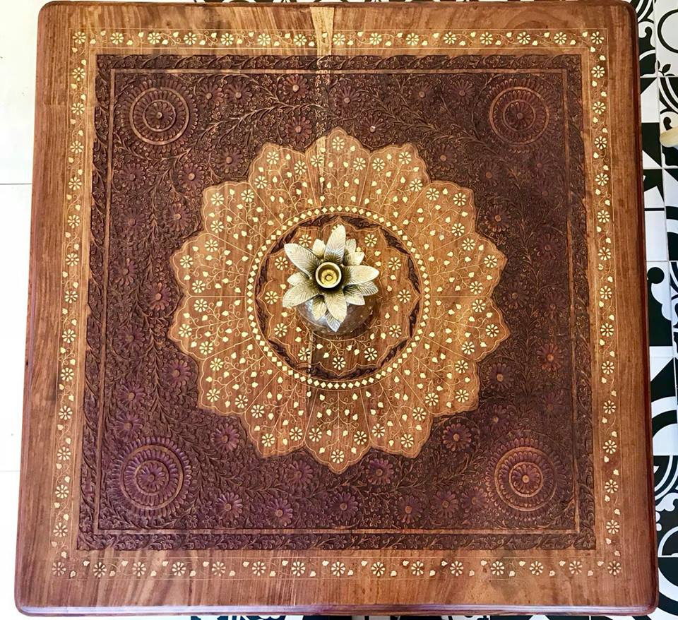 Mặt bàn nhỏ thoạt nhìn như một bức tranh nghệ thuật tuyệt đẹp nhờ sự phối kết hợp màu sắc trang trí và những họa tiết gỗ chạm khắc hoa nhí độc đáo.