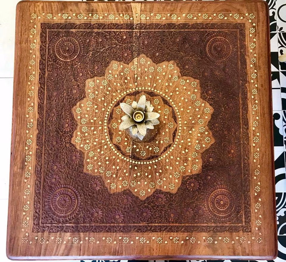 Mặt bàn nhỏ thoạt nhìn như một bức tranh nghệ thuật tuyệt đẹp nhờ sự phối kết hợp màu sắc trang trí và những họa tiết gỗ chạm khắc hoa nhí độc đáo.