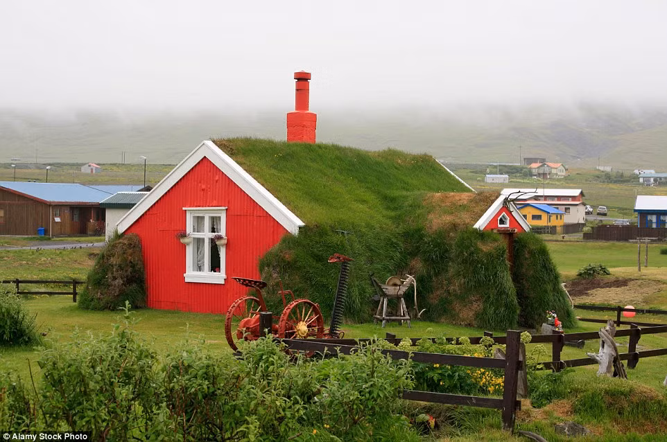 Ngôi nhà cỏ hiện đại, nổi bật lên màu xanh bởi những mảng tường màu đỏ.