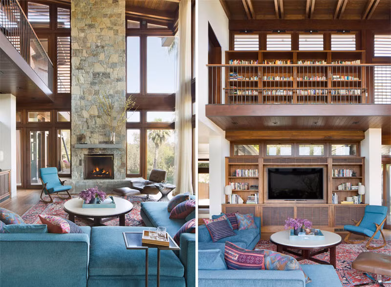 Phòng khách nổi bật với lò sưởi ốp đá và bộ ghế sofa màu xanh kết hợp thảm trải sàn có hoạt tiết và màu sắc bắt mắt.