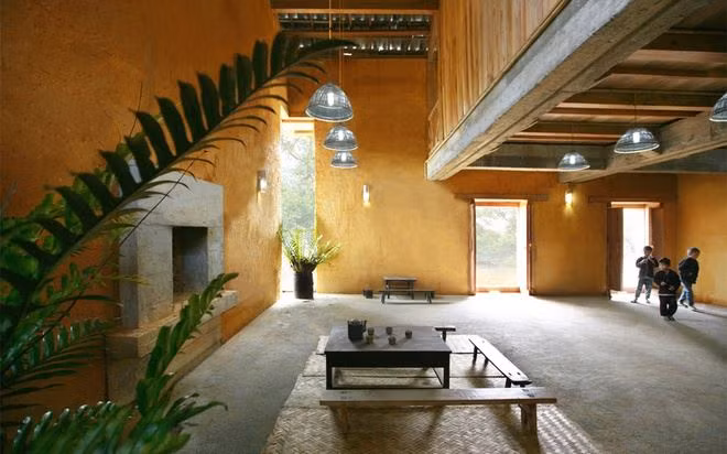 Nhà có 2 tầng, với tường đất dày 80 cm, có màu sắc, vật liệu thân thiện. Kết cấu nhà là khung bê tông kết hợp vi kèo gỗ. Công trình tiết kiệm năng lượng do sử dụng hệ ngói kép cách nhiệt, thu nước mưa tái sử dụng. Ảnh: Cafebiz.