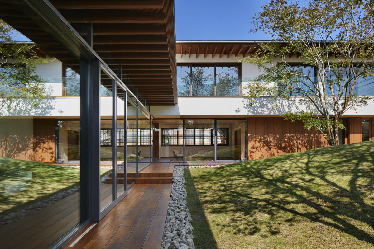 Cửa trượt bằng kính cao từ sàn đến trần làm mờ ranh giới giữa bên trong nhà và khu vườn bên ngoài.