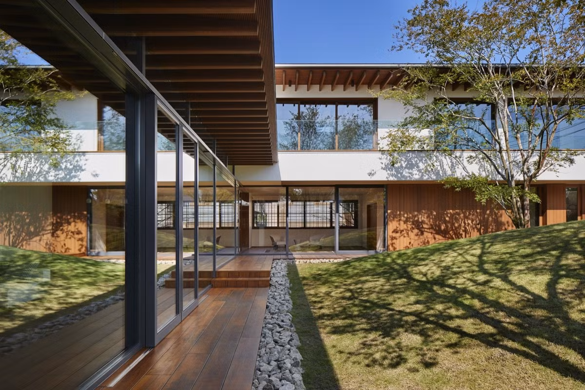 Cửa trượt bằng kính cao từ sàn đến trần làm mờ ranh giới giữa bên trong nhà và khu vườn bên ngoài.