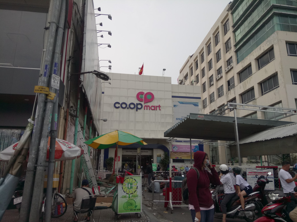Khach ngo ngang truoc tin Co.opmart Dinh Tien Hoang dong cua